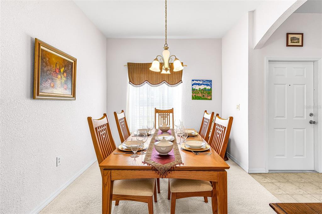 A dining room features a wooden table with six chairs, a chandelier, and wall art — 2358 PILGER AVENUE, NORTH PORT, FL