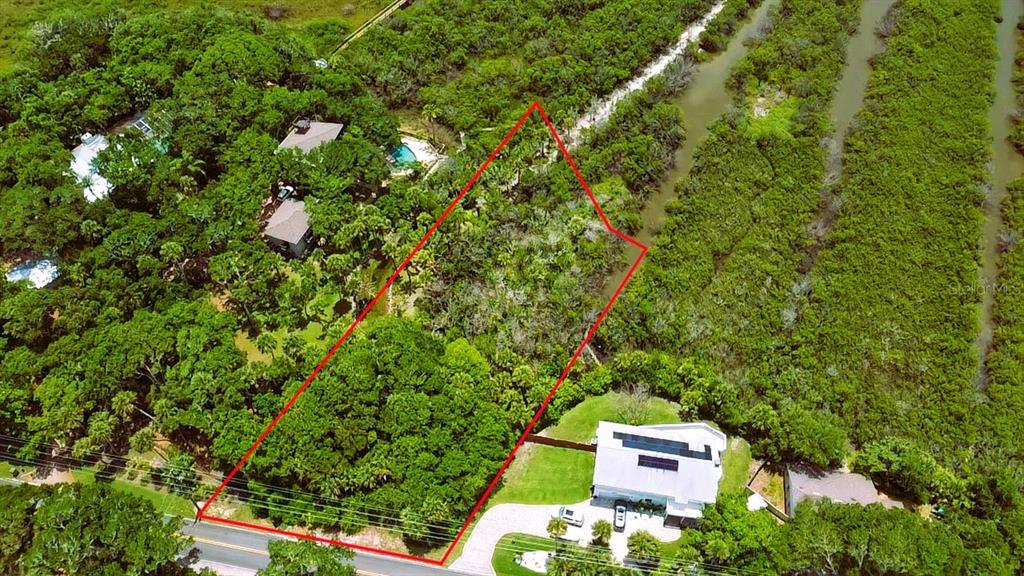 An aerial view shows a rectangular wooded lot outlined in red next to residential homes — 4168 SAXON DRIVE, NEW SMYRNA BEACH, FL