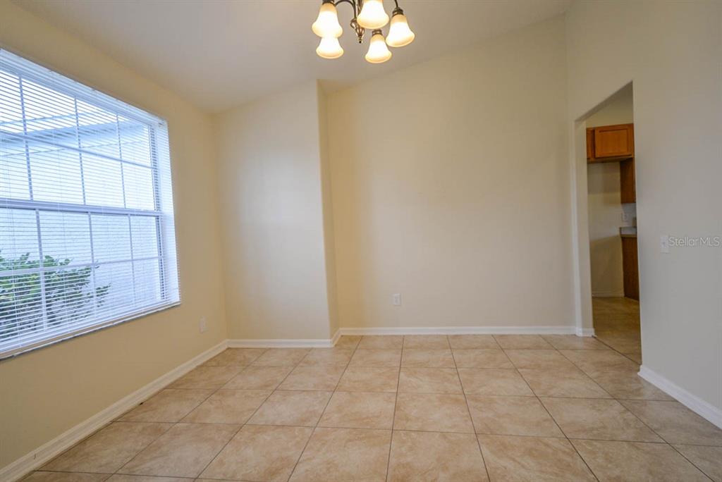 An empty dining room features beige tile flooring, a window with blinds, and a chandelier — 1607 AVONDALE RIDGE DRIVE, PLANT CITY, FL