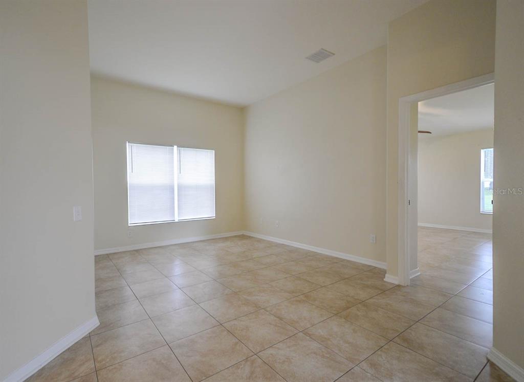 An empty room with beige tile flooring, light-colored walls, and a window with blinds — 1607 AVONDALE RIDGE DRIVE, PLANT CITY, FL