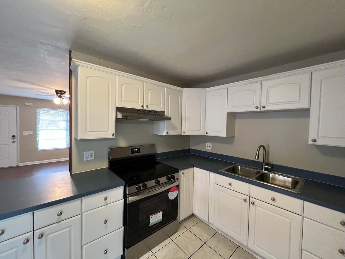 A kitchen with white cabinets, dark blue countertops, stainless steel appliances, and tiled flooring — DAVIE, FL