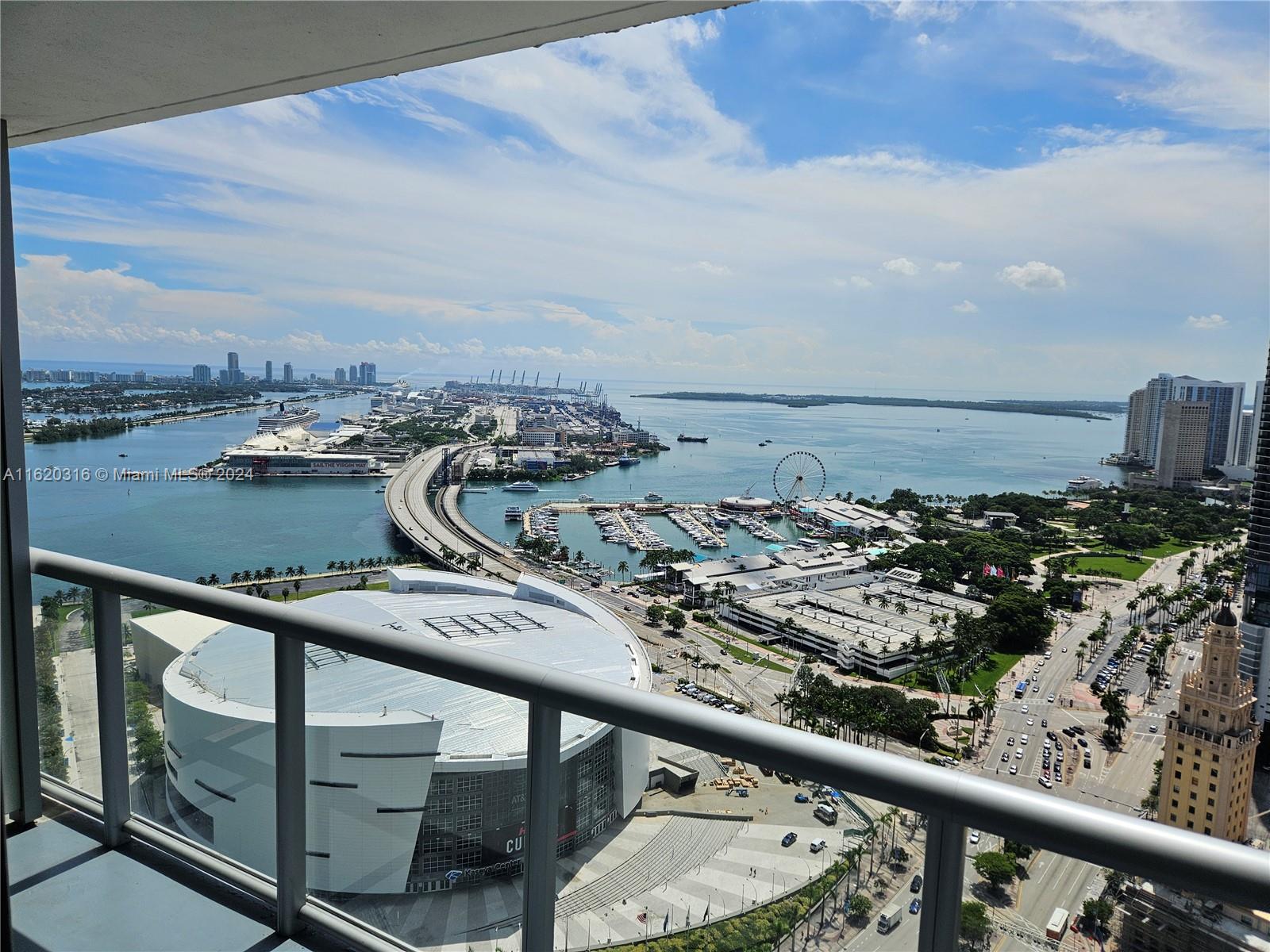A high-angle view from a balcony overlooking the Kaseya Center, PortMiami, and the bay — 888 Biscayne Blvd # 2701, Miami FL 33132, MIAMI, FL