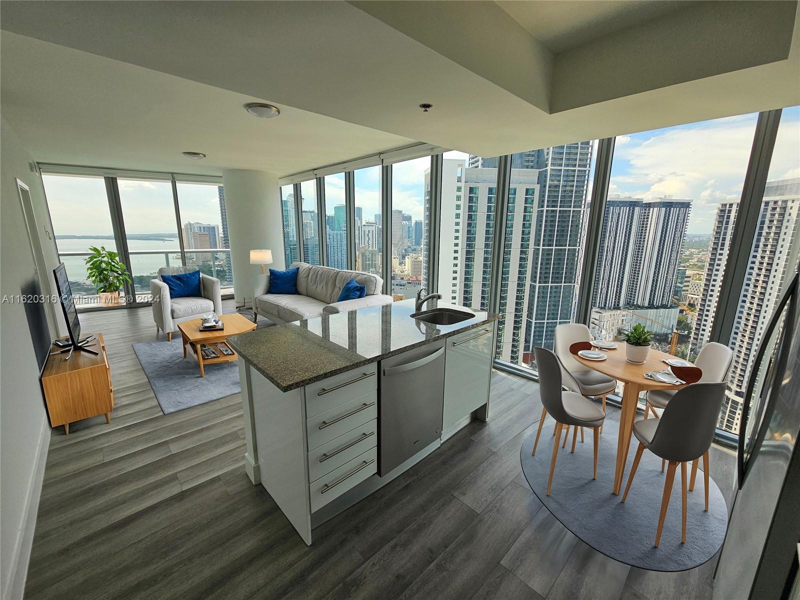An open-concept apartment living area features a kitchen island, dining set, and floor-to-ceiling windows — 888 Biscayne Blvd # 2701, Miami FL 33132, MIAMI, FL