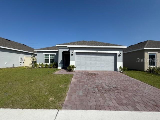 A single-story house features a gray exterior, a two-car garage, and a brick paver driveway — 3649 YARIAN DRIVE, HAINES CITY, FL