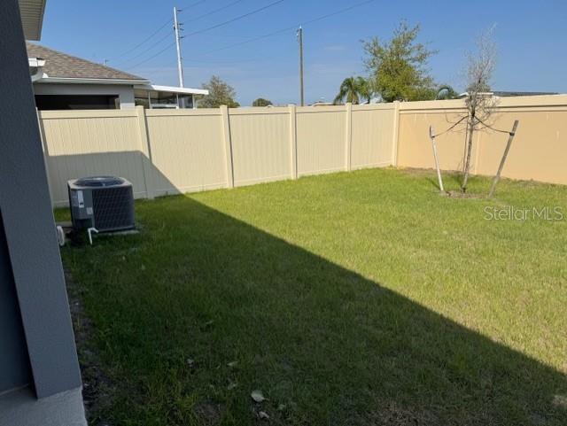 A backyard features a green lawn, a tan vinyl fence, and an air conditioning unit — 3649 YARIAN DRIVE, HAINES CITY, FL