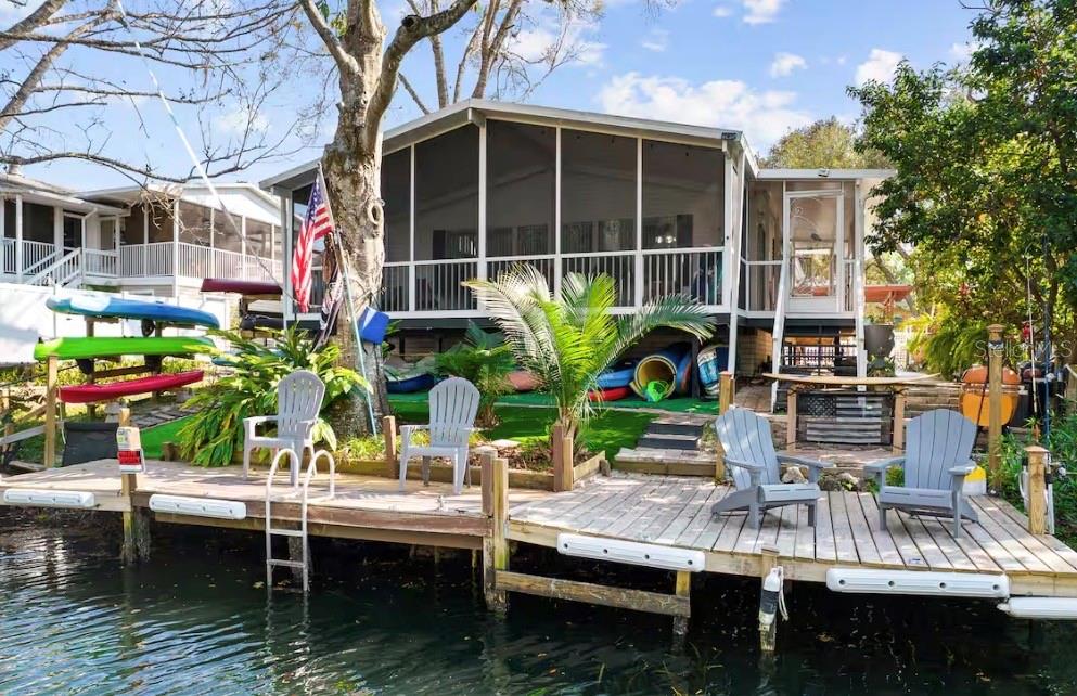 A waterfront house with a screened porch, wooden dock, and several kayaks stored underneath — 6331 THEODAN STREET, WEEKI WACHEE, FL