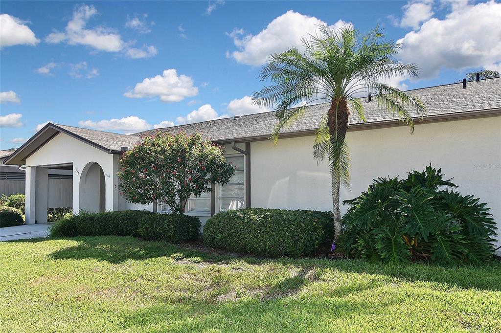 A single-story house with a palm tree, manicured shrubs, and a covered entryway — 1527 STEWART DRIVE UNIT 115, SARASOTA, FL
