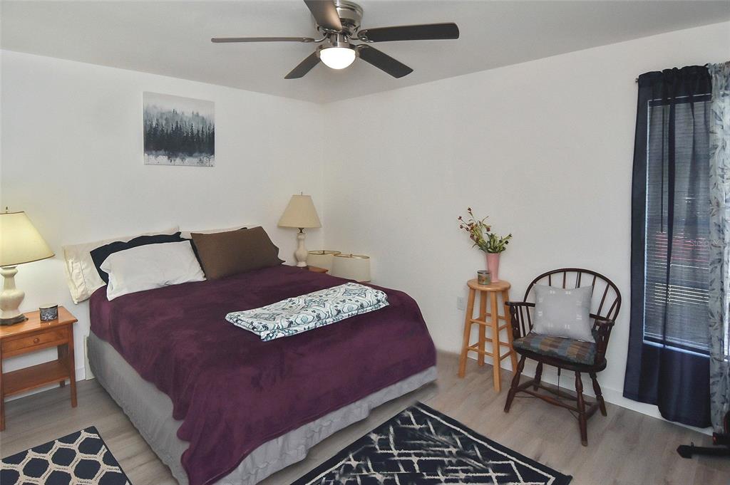 A bedroom features a bed with a purple cover, a ceiling fan, and a wooden chair — 1527 STEWART DRIVE UNIT 115, SARASOTA, FL