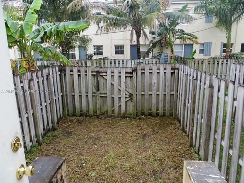 A small, fenced-in backyard area with grass and palm trees behind a residential building — 436 NW 84th Ter # 436, Miami FL 33150, MIAMI, FL