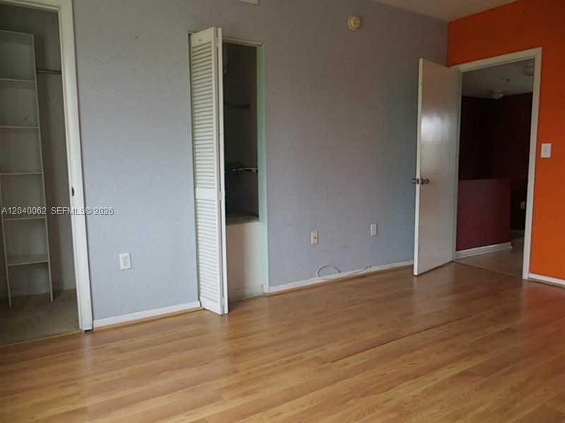 A room with light wood flooring, gray walls, a closet, and an open doorway — 436 NW 84th Ter # 436, Miami FL 33150, MIAMI, FL