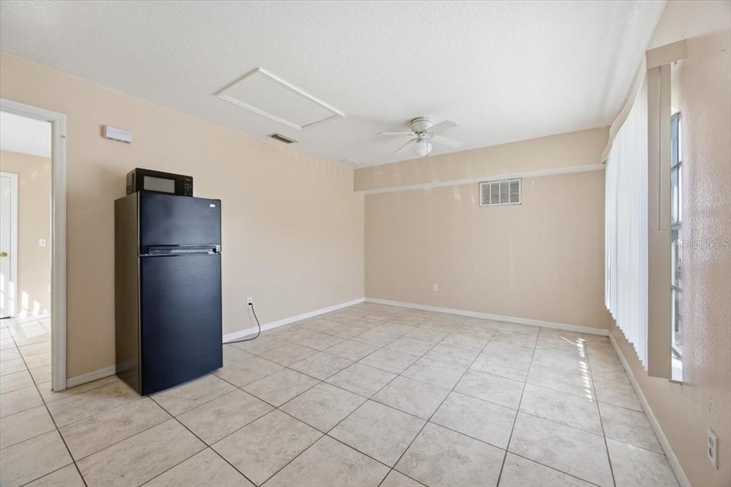 An empty room with beige walls, tile flooring, a ceiling fan, and a black refrigerator — 2918 FAN PALM DRIVE Front unit, DAVENPORT, FL
