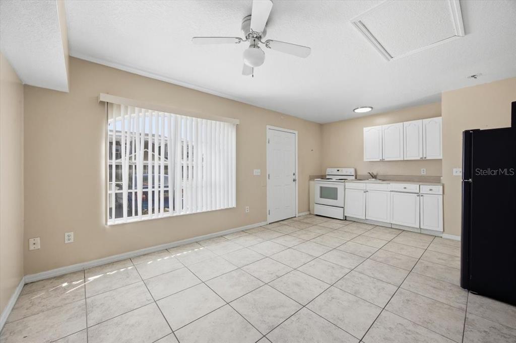 A kitchen and dining area with white cabinets, tile flooring, and a ceiling fan — 2918 FAN PALM DRIVE Front unit, DAVENPORT, FL