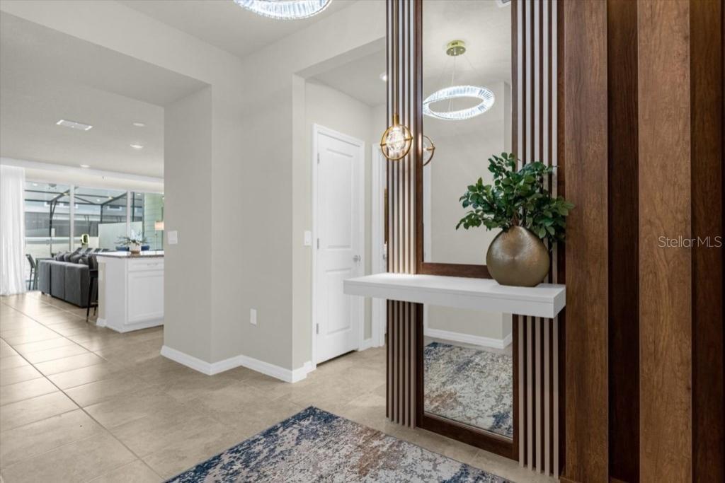 A modern entryway features a white floating console table, a vertical wood-slat accent wall, and mirror — 4306 LANA AVENUE, DAVENPORT, FL