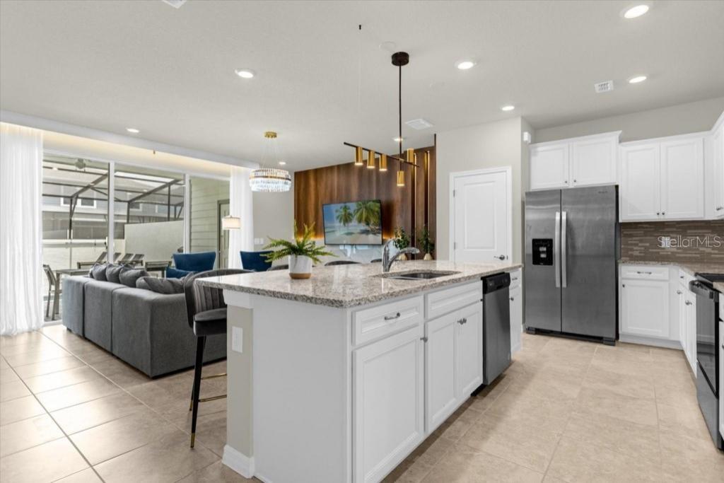 A modern kitchen with white cabinets, granite countertops, and an island overlooks a living area — 4306 LANA AVENUE, DAVENPORT, FL