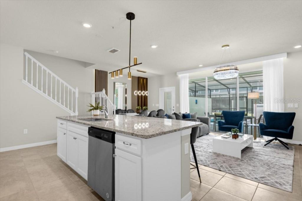 A kitchen island with granite countertops overlooks a living room with blue chairs and tile floors — 4306 LANA AVENUE, DAVENPORT, FL