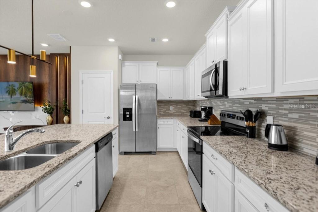 A kitchen features white cabinets, granite countertops, stainless steel appliances, and a central island — 4306 LANA AVENUE, DAVENPORT, FL