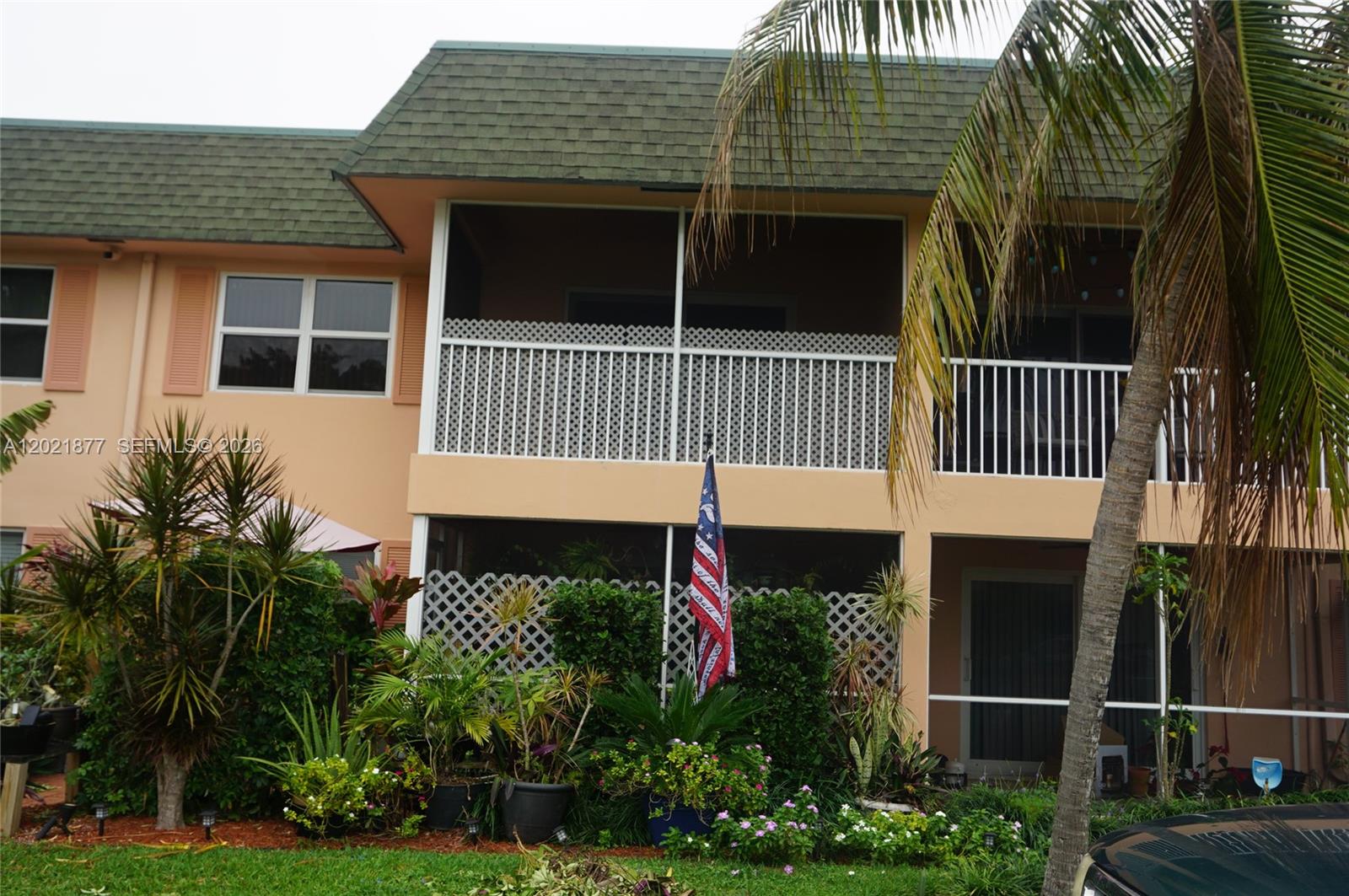 A two-story building features screened balconies, a green shingled roof, and lush landscaping — 770 SE 2nd Ave # A205, Deerfield Beach FL 33441, DEERFIELD BEACH, FL