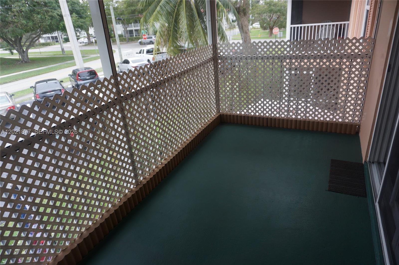 A balcony with green flooring and beige lattice privacy screens overlooks a parking lot — 770 SE 2nd Ave # A205, Deerfield Beach FL 33441, DEERFIELD BEACH, FL
