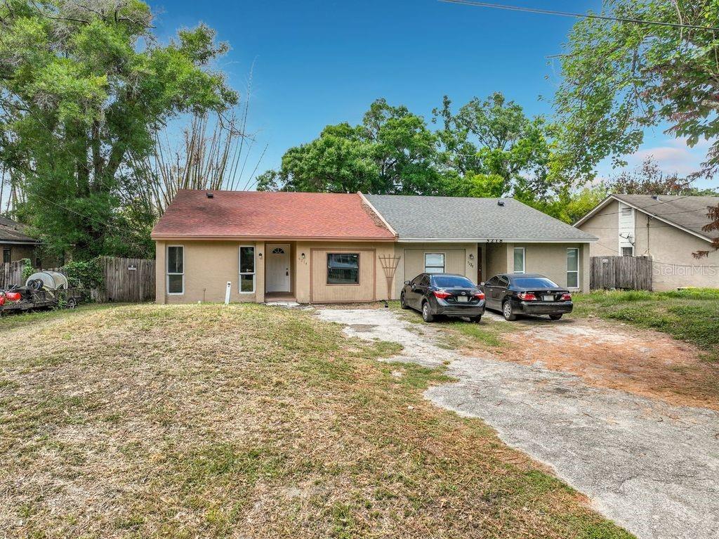 A single-story house with a two-tone roof, tan stucco exterior, and a concrete driveway — 5214 2ND STREET, ORLANDO, FL