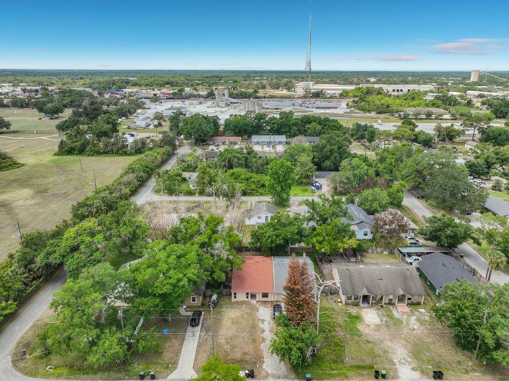 An aerial view shows a residential street with houses, trees, and a distant industrial facility — 5214 2ND STREET, ORLANDO, FL