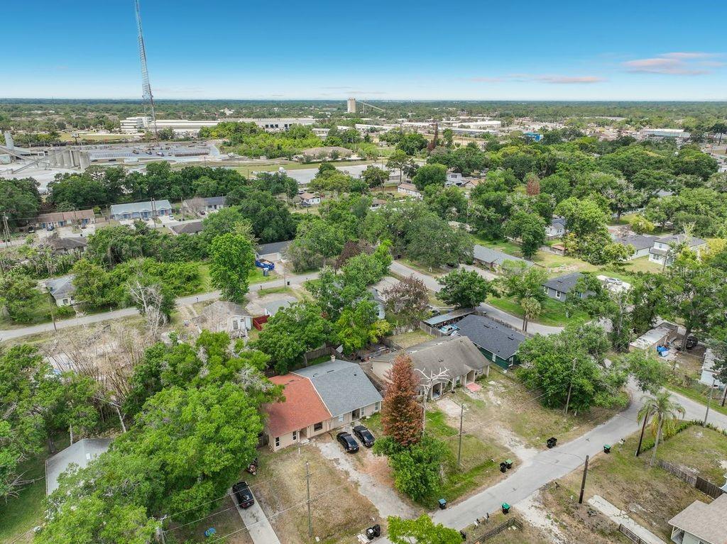 An aerial view of a residential neighborhood featuring houses with trees and a nearby industrial site — 5214 2ND STREET, ORLANDO, FL