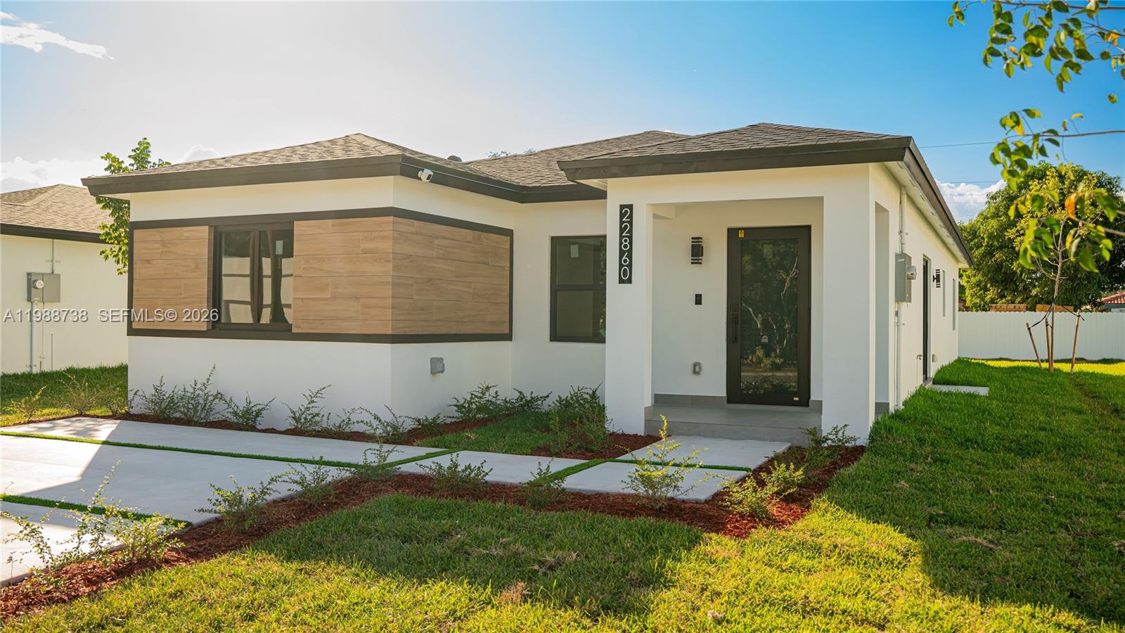 A modern single-story house with white stucco walls, wood-look siding accents, and a dark roof — 22840 SW 122nd PL, Miami FL 33170, MIAMI, FL
