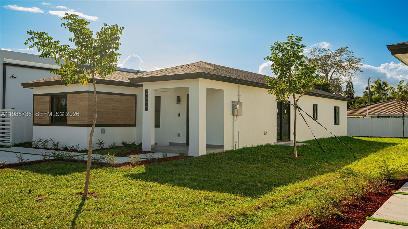 A modern single-story house with white stucco walls and wood-look siding accents — 22840 SW 122nd PL, Miami FL 33170, MIAMI, FL