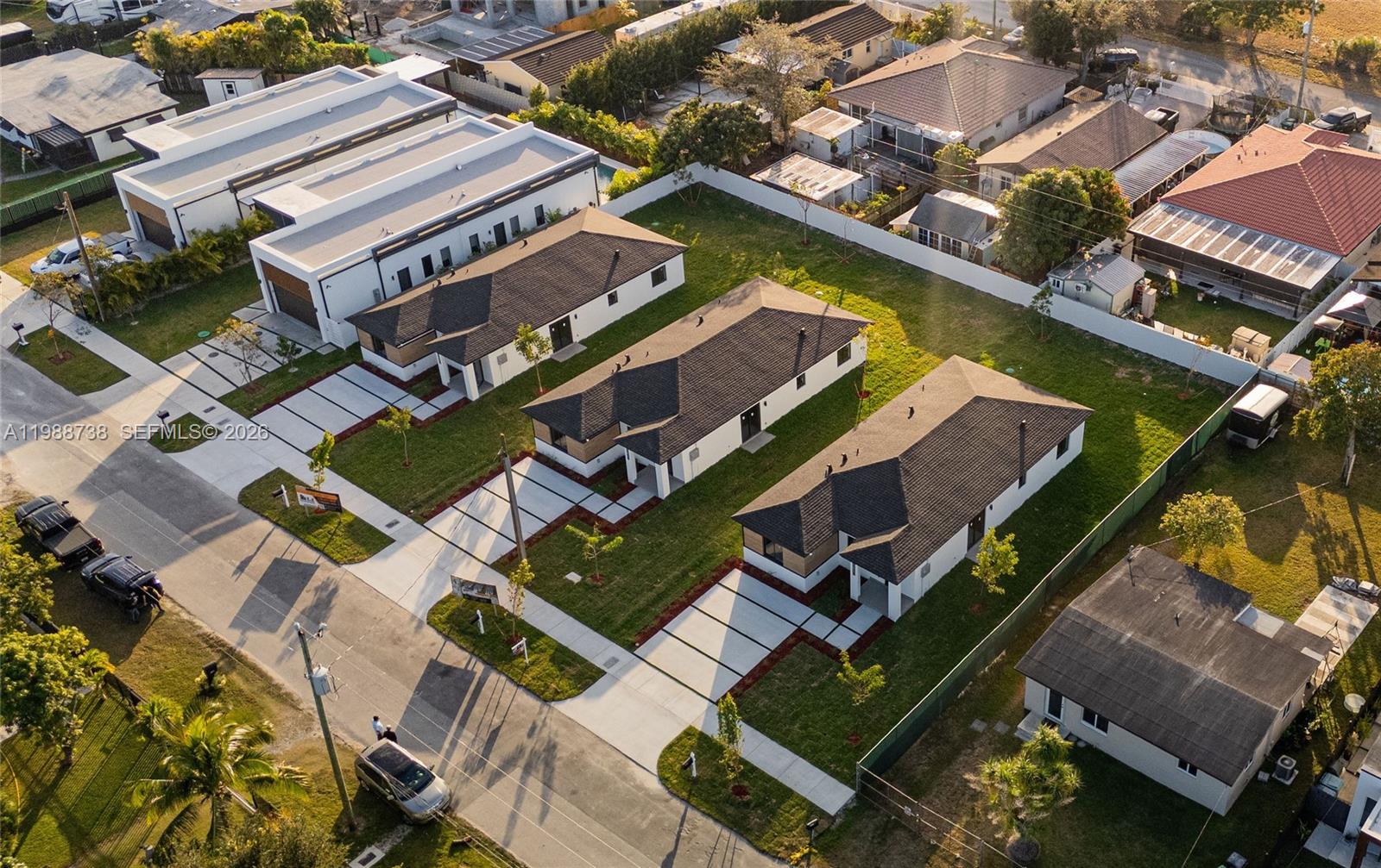 An aerial view shows three modern single-story houses with dark roofs and concrete driveways — 22840 SW 122nd PL, Miami FL 33170, MIAMI, FL