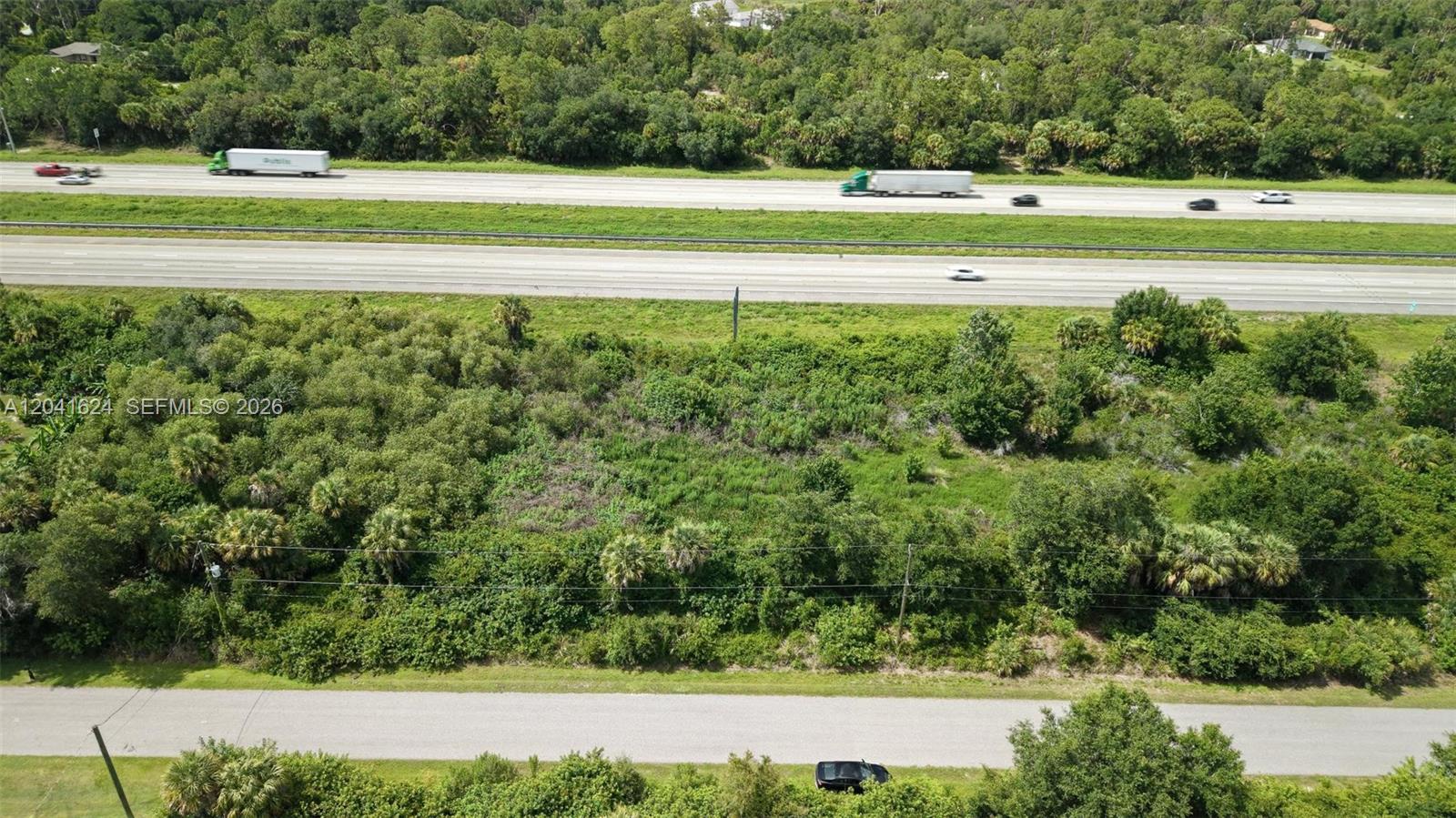 An aerial view shows a vacant, wooded lot situated between a road and a highway — 0 SNUG ST, North Port FL 34286, NORTH PORT, FL