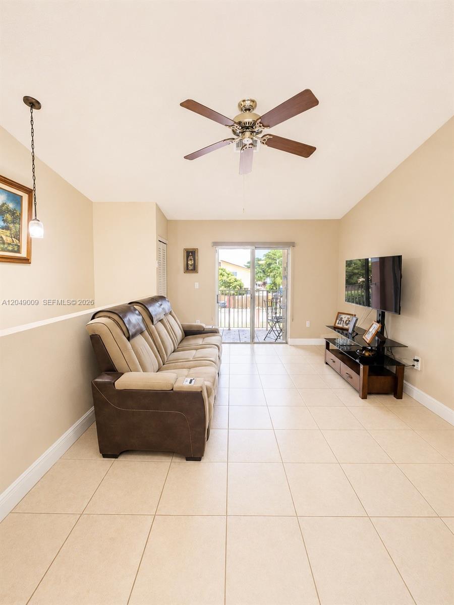 A living room features a tan sofa, a television on a stand, and tile flooring — 5800 W 18th Ln, Hialeah FL 33012, HIALEAH, FL