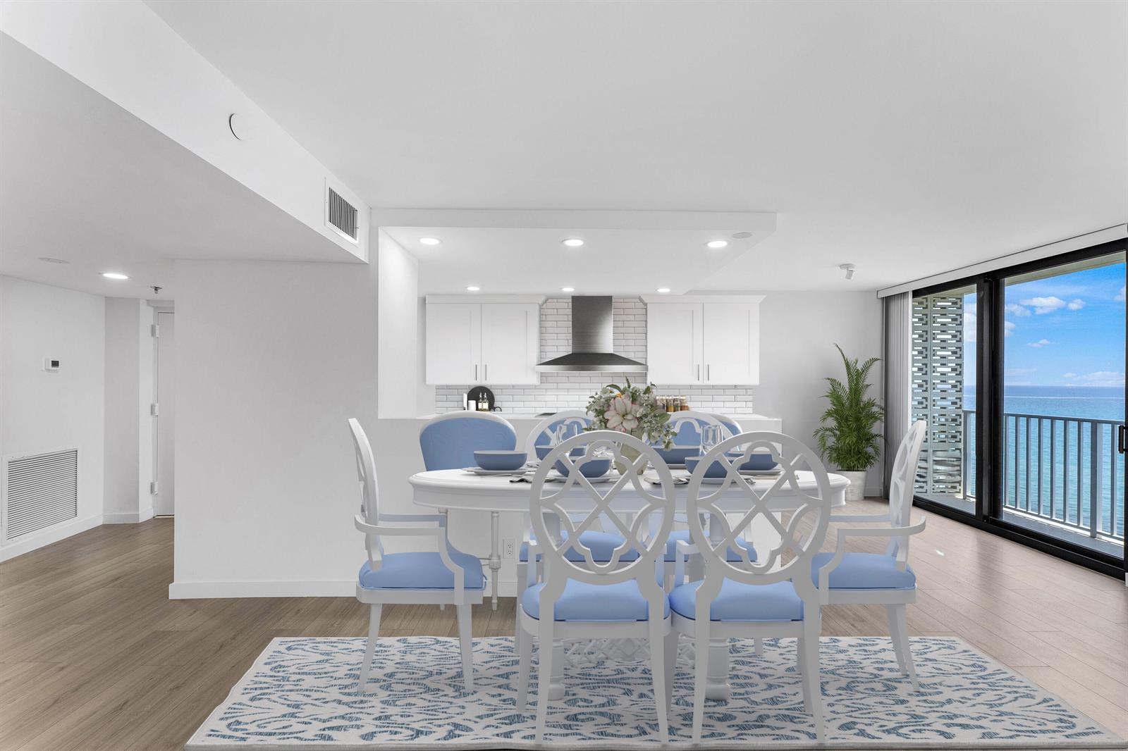 A dining area with a white table and chairs sits before an open kitchen and balcony — 3360 S Ocean Boulevard, Palm Beach FL 33480, PALM BEACH, FL