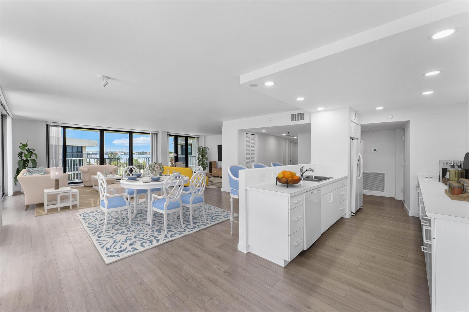 An open-concept living and dining area features white cabinetry, light wood flooring, and balcony views — 3360 S Ocean Boulevard, Palm Beach FL 33480, PALM BEACH, FL