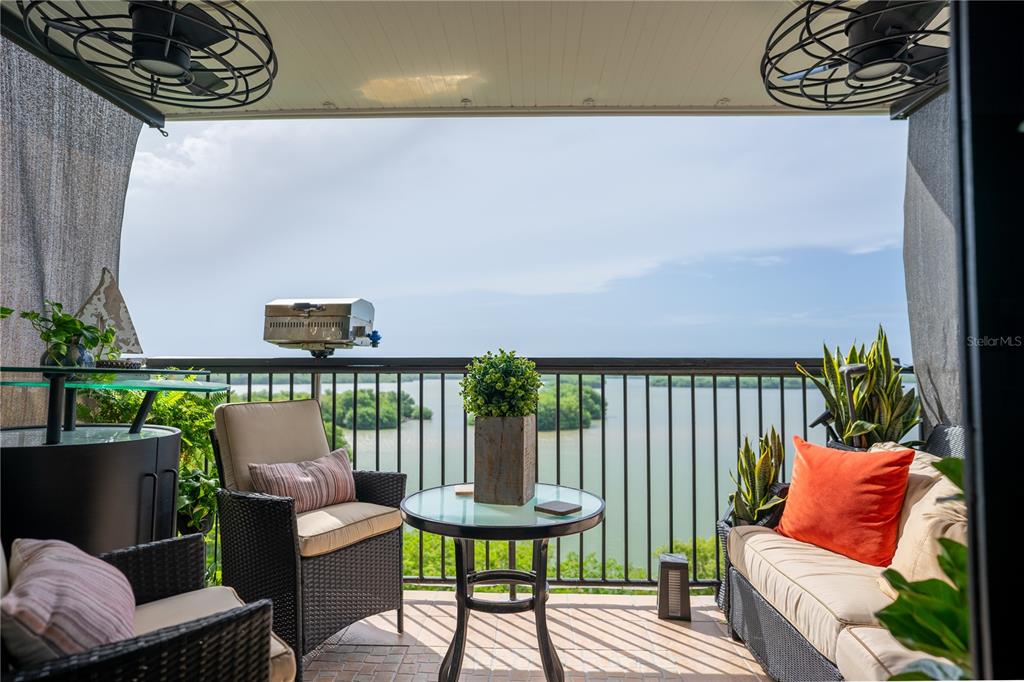 A covered balcony features wicker furniture, a small dining table, and a scenic water view — 1 CLUB COSTA MARINA UNIT 8-G, CAROLINA, PR