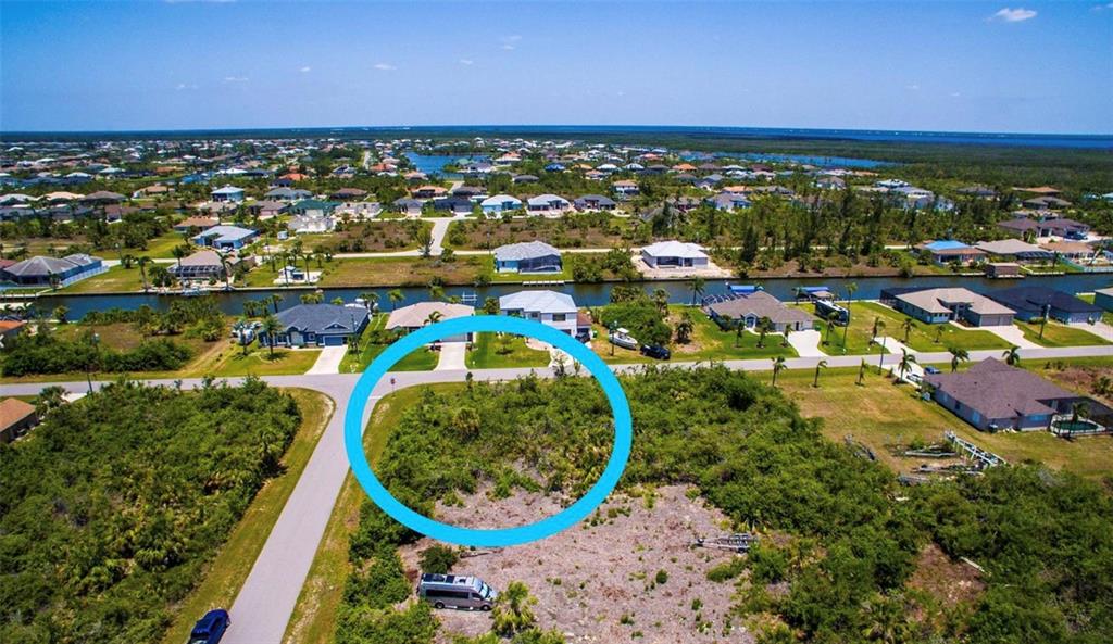 An aerial view of a vacant, brush-covered residential lot highlighted by a blue circle — 15531 AQUA CIRCLE, PORT CHARLOTTE, FL