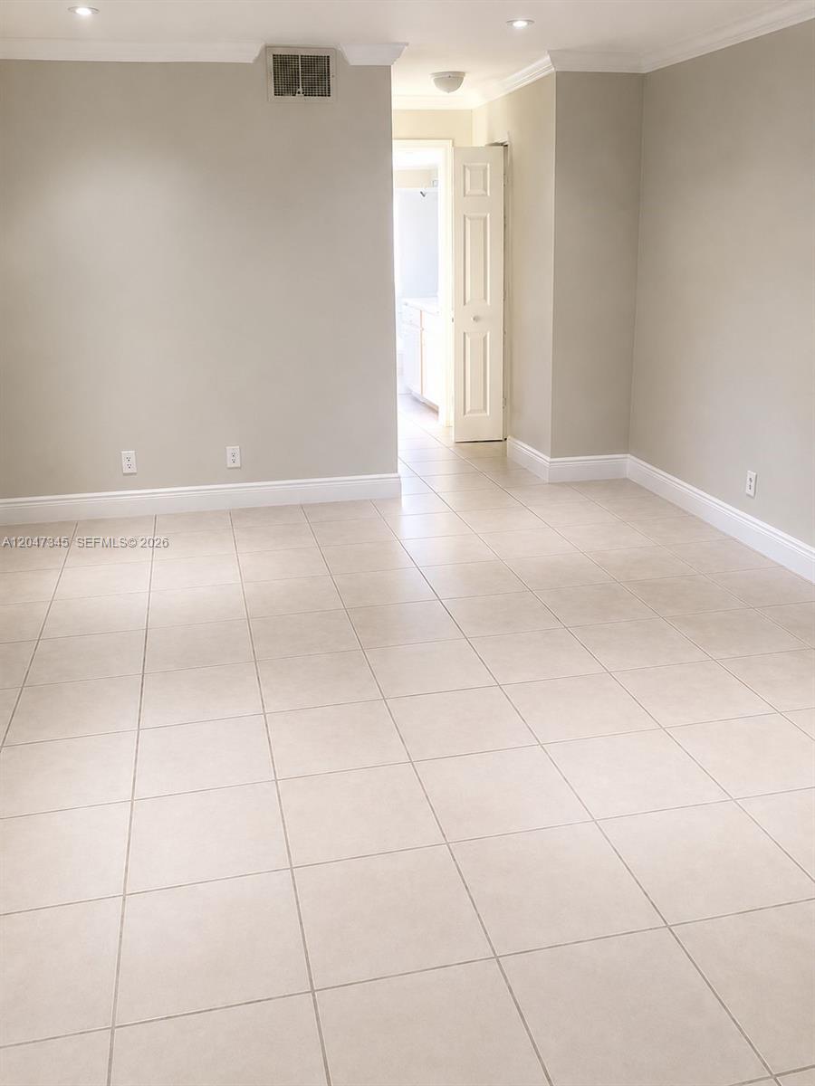 An empty room with light-colored tile flooring, beige walls, and an open doorway leading inside — 500 NE 2nd St # 419, Dania Beach FL 33004, DANIA BEACH, FL