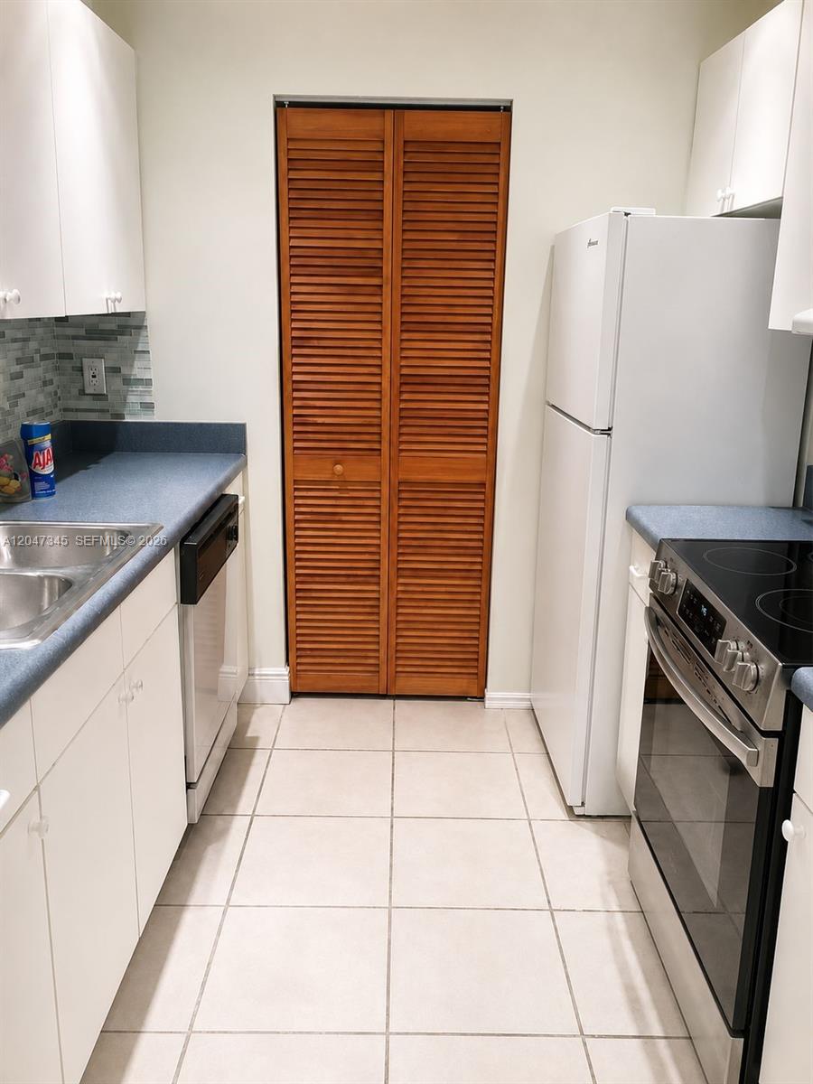 A galley-style kitchen features white cabinets, blue countertops, stainless steel appliances, and a wooden closet — 500 NE 2nd St # 419, Dania Beach FL 33004, DANIA BEACH, FL