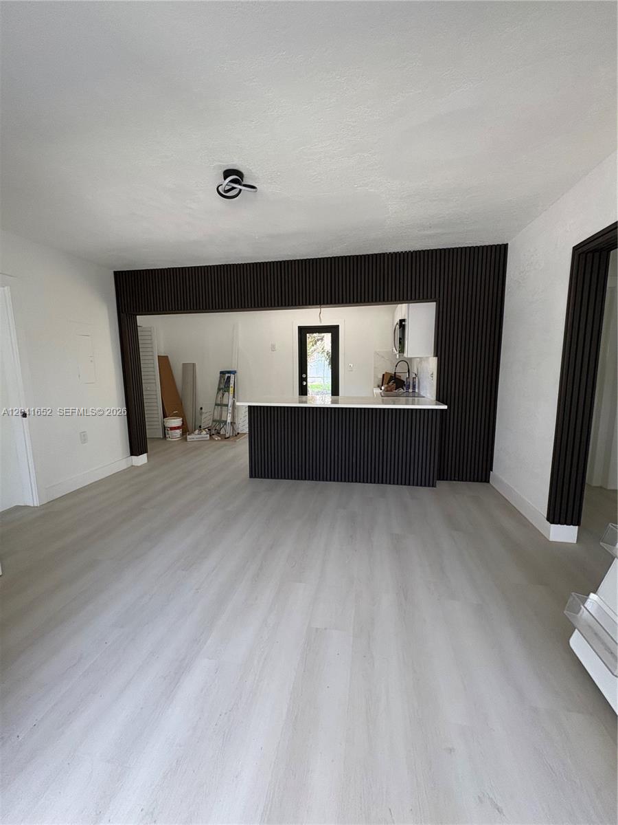 A living area features light wood-look flooring and a dark wood-slatted accent wall with a bar — 811 NW 65th St, Miami FL 33150, MIAMI, FL