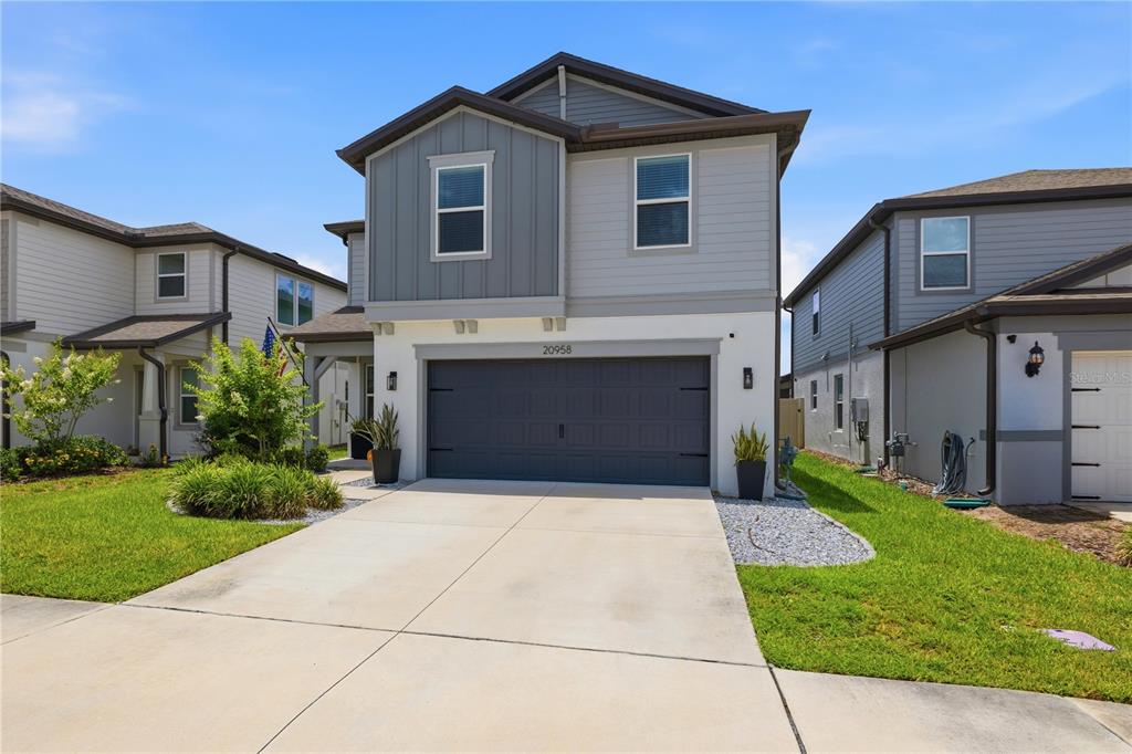 A two-story house with a gray garage, light-colored siding, and a concrete driveway — 20958 DRAKE ELM DRIVE, LAND O LAKES, FL