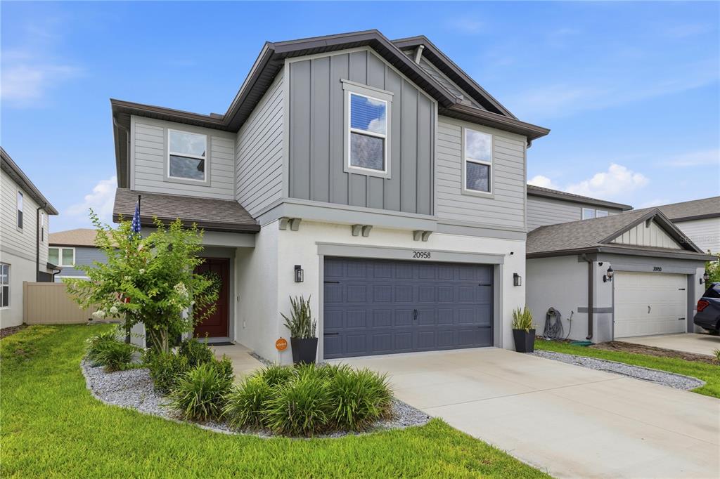 A two-story house with a gray garage, white stucco, and gray siding exterior — 20958 DRAKE ELM DRIVE, LAND O LAKES, FL