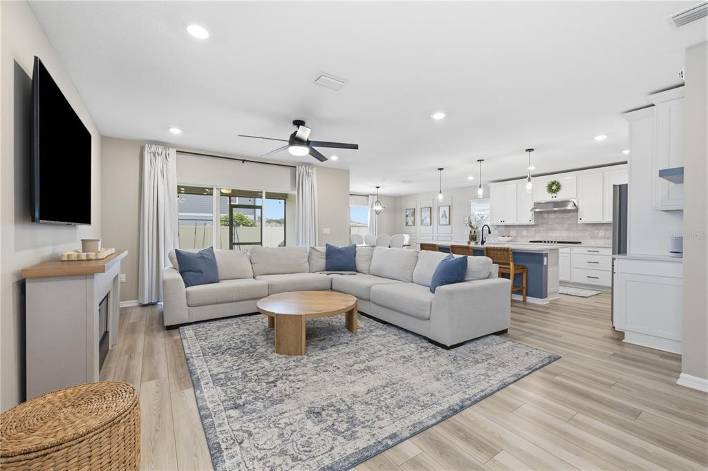 An open-concept living room features a sectional sofa, a round coffee table, and a kitchen — 20958 DRAKE ELM DRIVE, LAND O LAKES, FL