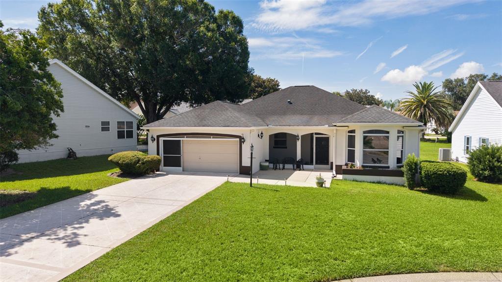 A single-story house with a garage, front patio, and lawn under a sunset sky — 1012 DIEGO COURT, LADY LAKE, FL