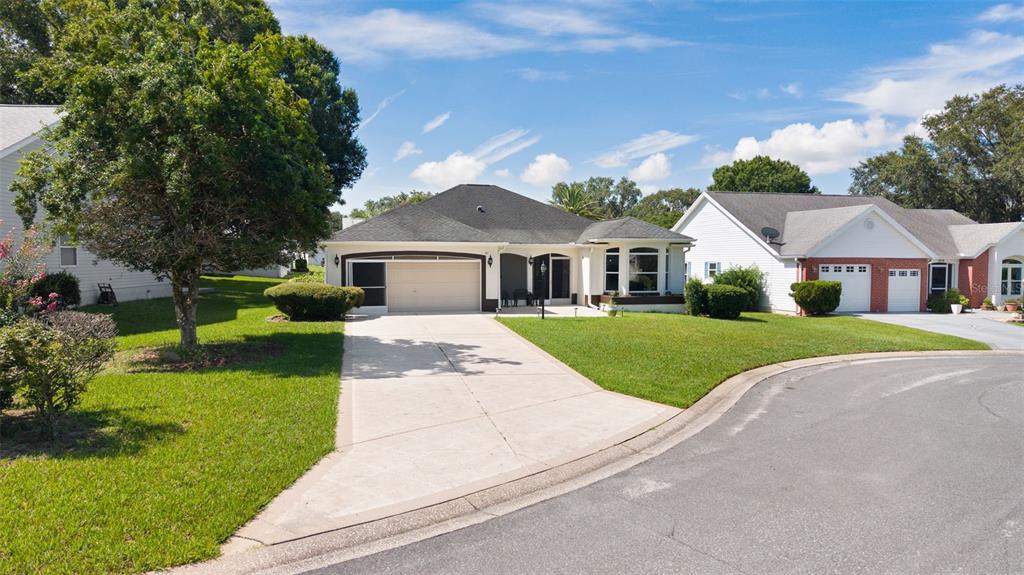 A single-story house with a beige exterior, dark roof, and concrete driveway in a neighborhood — 1012 DIEGO COURT, LADY LAKE, FL