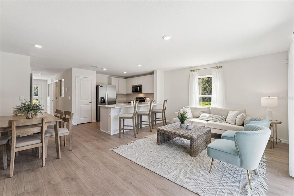 An open-concept living room and kitchen featuring light wood flooring and white cabinetry — 717 PRESTON COVE DRIVE, ST CLOUD, FL