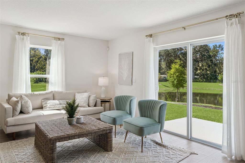A living room features a beige sofa, two teal chairs, a wicker coffee table, and sliding doors — 717 PRESTON COVE DRIVE, ST CLOUD, FL