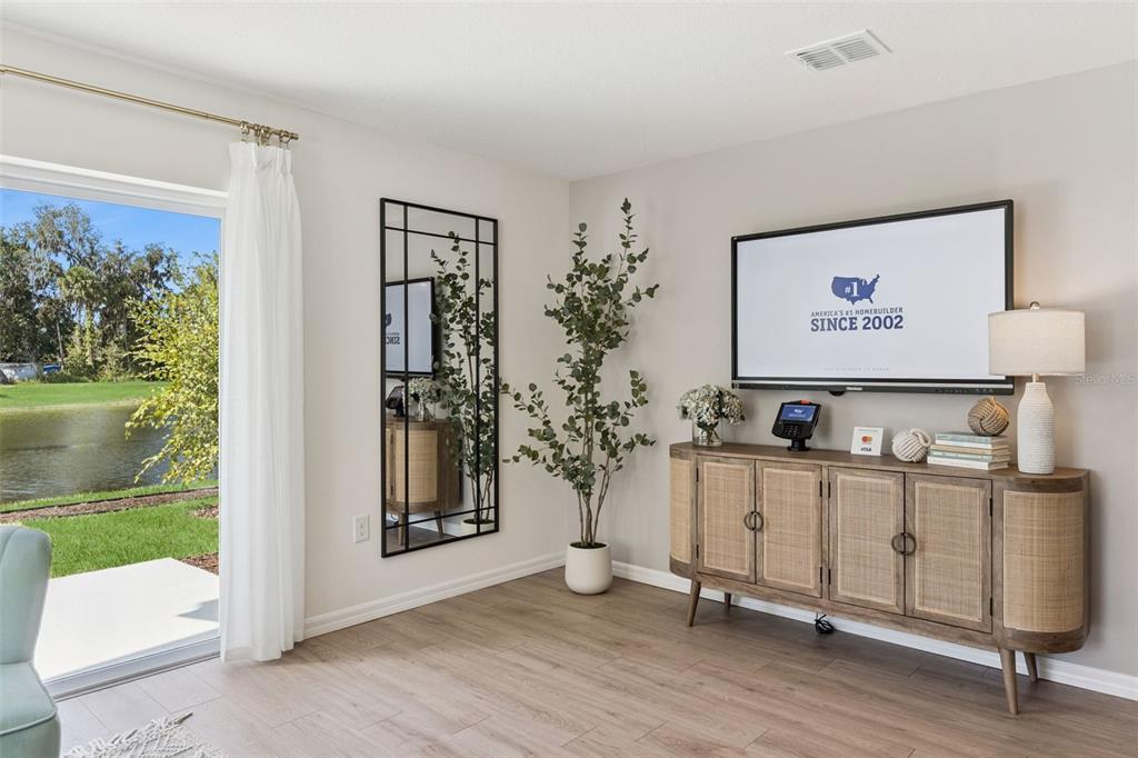 A living room features a media console, a wall-mounted television, a mirror, and sliding doors — 717 PRESTON COVE DRIVE, ST CLOUD, FL