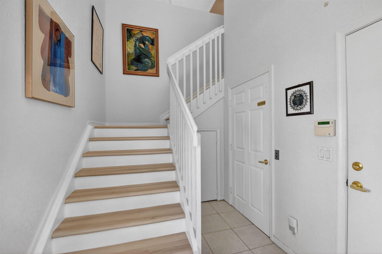 A staircase with light wood treads and white railings leads up from a tiled foyer — 7910 Laina Lane # 3, Boynton Beach FL 33437, BOYNTON BEACH, FL