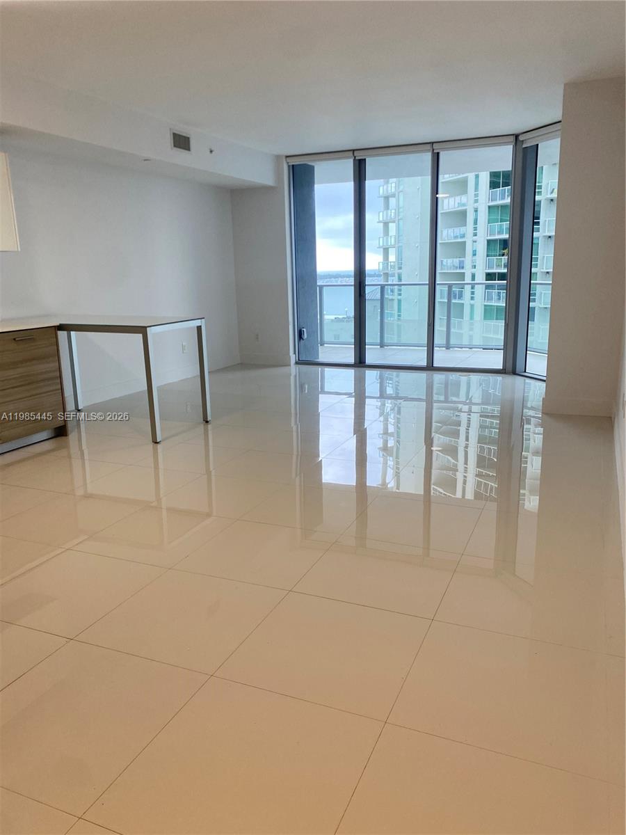 A bright, open-concept living area features white tile flooring, a kitchen island, and floor-to-ceiling windows — 1300 Brickell Bay Dr # 1903, Miami FL 33131, MIAMI, FL