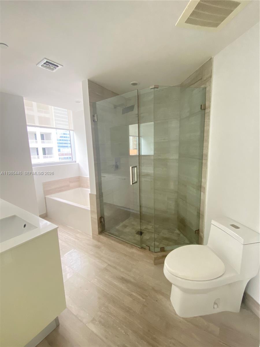 A modern bathroom features a glass-enclosed shower, a soaking tub, and a white toilet — 1300 Brickell Bay Dr # 1903, Miami FL 33131, MIAMI, FL
