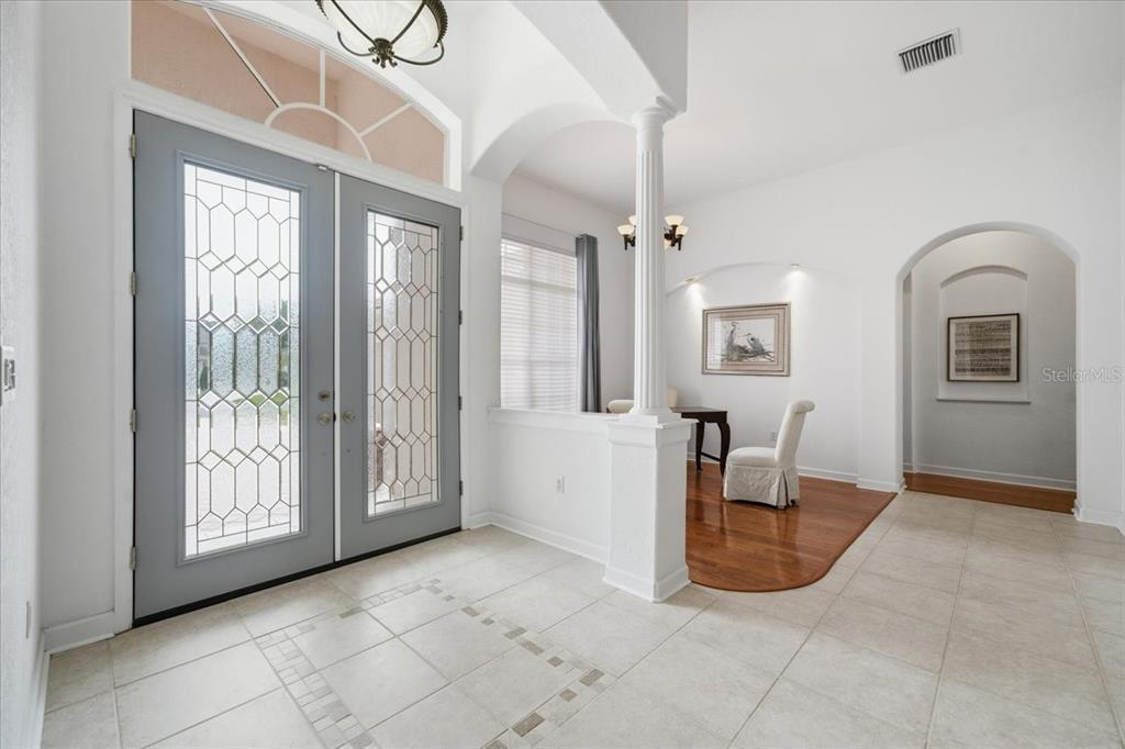 A bright entryway features light tile flooring, a gray double door, and a white column — 5021 CHAMPIONSHIP CUP LANE, SPRING HILL, FL