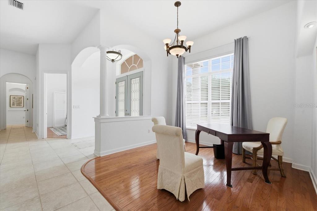 A dining room with hardwood floors, a chandelier, and a desk with two chairs — 5021 CHAMPIONSHIP CUP LANE, SPRING HILL, FL
